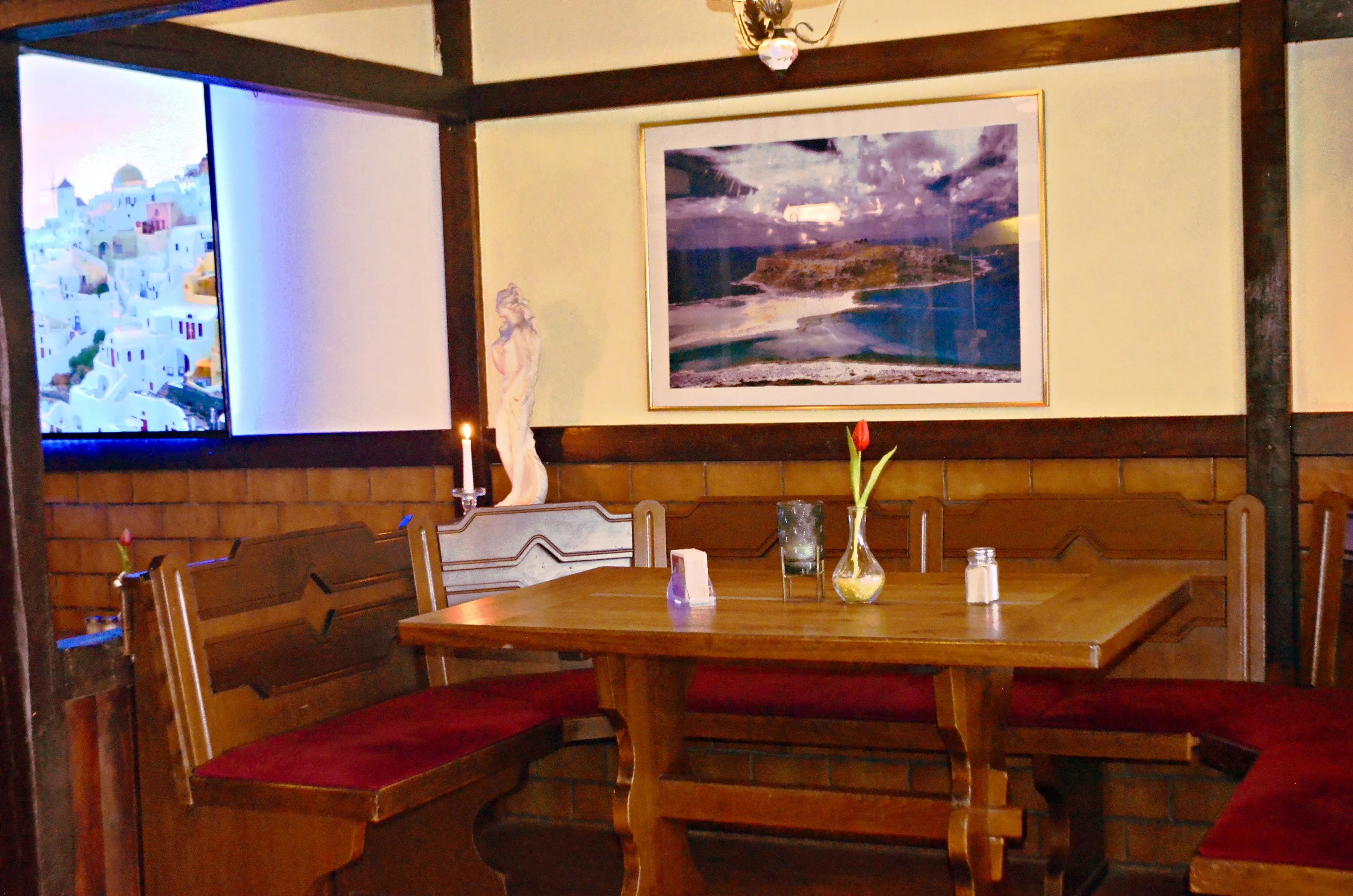 Sitznische mit Holzbank, Kerze und Tulpe, an der Wand ein Bild von Kreta